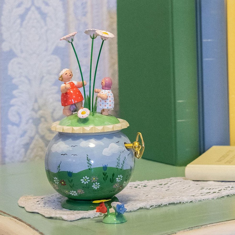 Spieldose mit Frühlingsmotiv auff einer Kommode mit Büchern und einer Tulpenvase