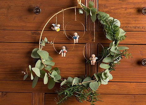 [Translate to Niederländisch:] Weihnachtskranz mit handgefertigten Margeritenengeln an braunem Schrank