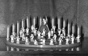 [Translate to Niederländisch:] Schwarz-Weiß-Aufnahme vom Engelorchester mit Madonna auf einem Engelberg. Auf den unteren Stufen die Engelmusikanten. An oberster Stelle die Madonna mit Schleier und im langen Kleid. Im Hintergrund Kerzen. 