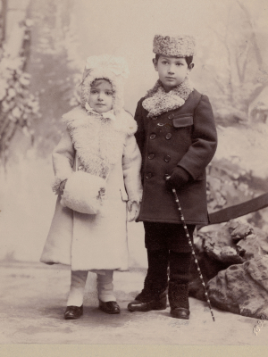 [Translate to Niederländisch:] Historische Schwarz-Weiß-Fotografie. Olly und Herbert als Kinder. Olly trägt einen hellen Wintermantel, Herbert einen dunklen.