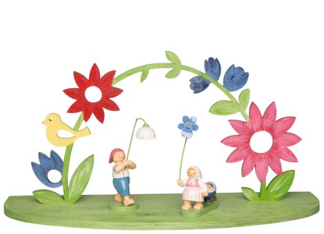 Dekorative Bühne mit farbenfroh bemaltem Bogen aus Holzblüten. In der Mitte stehen zwei Figuren, die Blumen halten