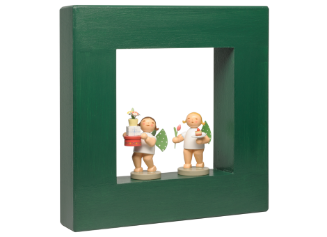 Zwei kleine Engelfiguren mit grünen Flügeln in einem grünen quadratischen Rahmen, eine hält Geschenke, die andere eine Tulpe und ein Törtchen